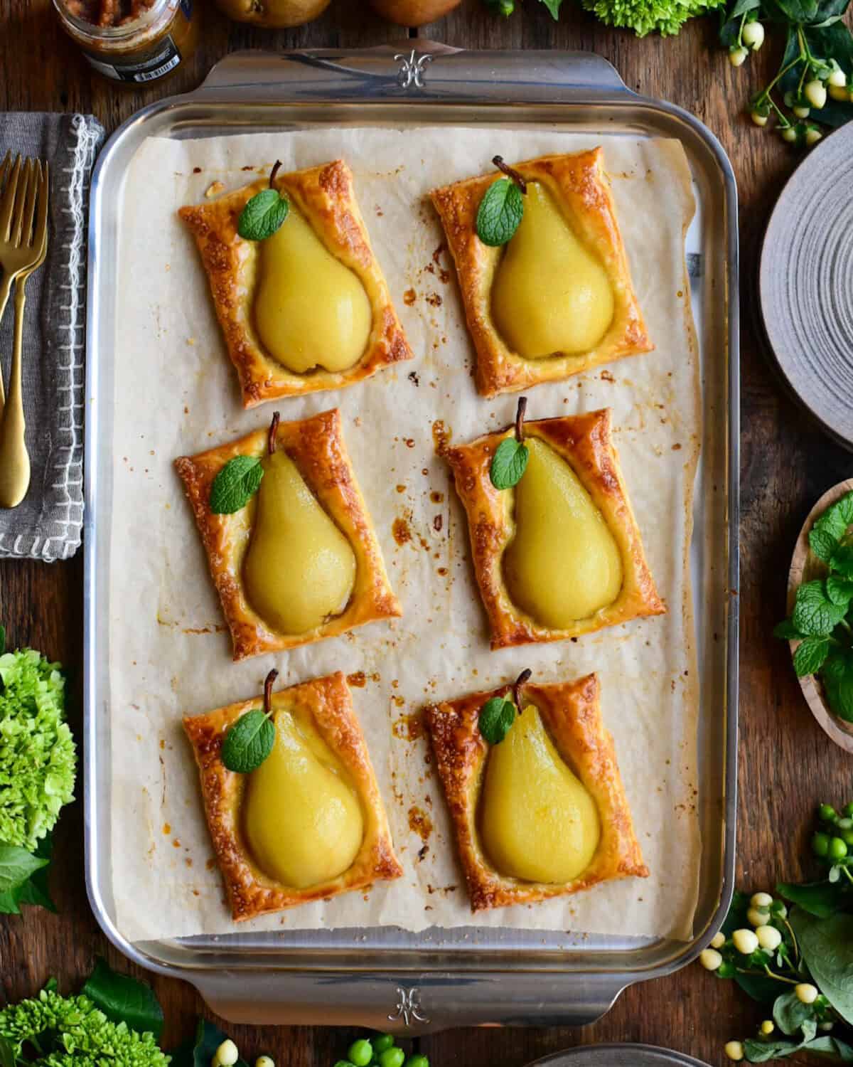 Six pear puff pastry desserts with a mint leaf.
