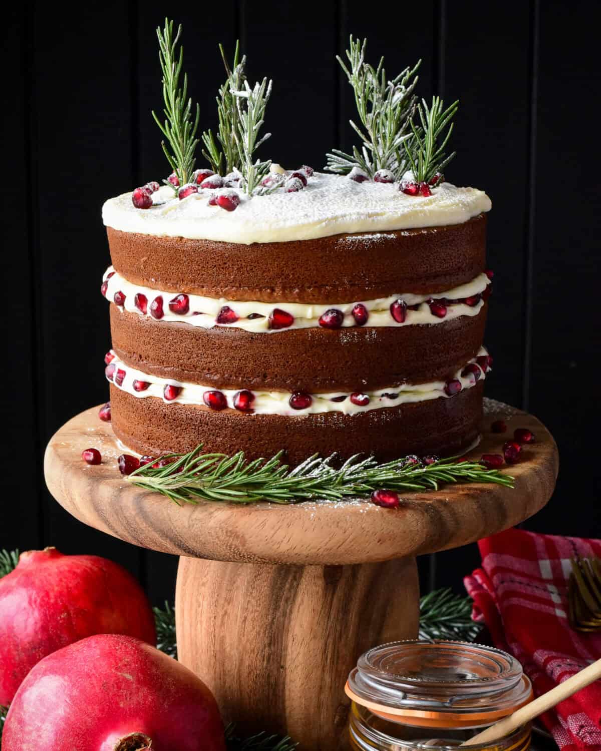 A three layer Honey Cake with Cream Cheese Frosting decorated with rosemary trees and pomegranate arils.