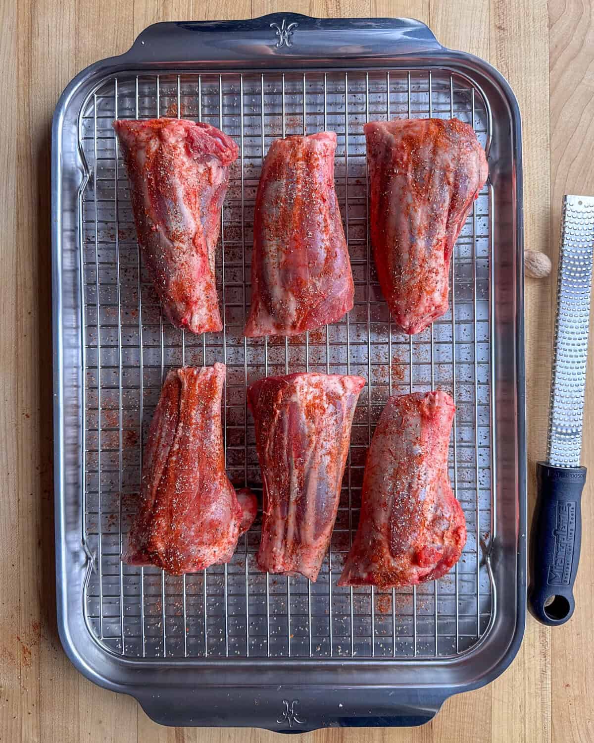 Pat the lamb shanks dry with paper towels, then season with paprika, salt, pepper, and nutmeg.