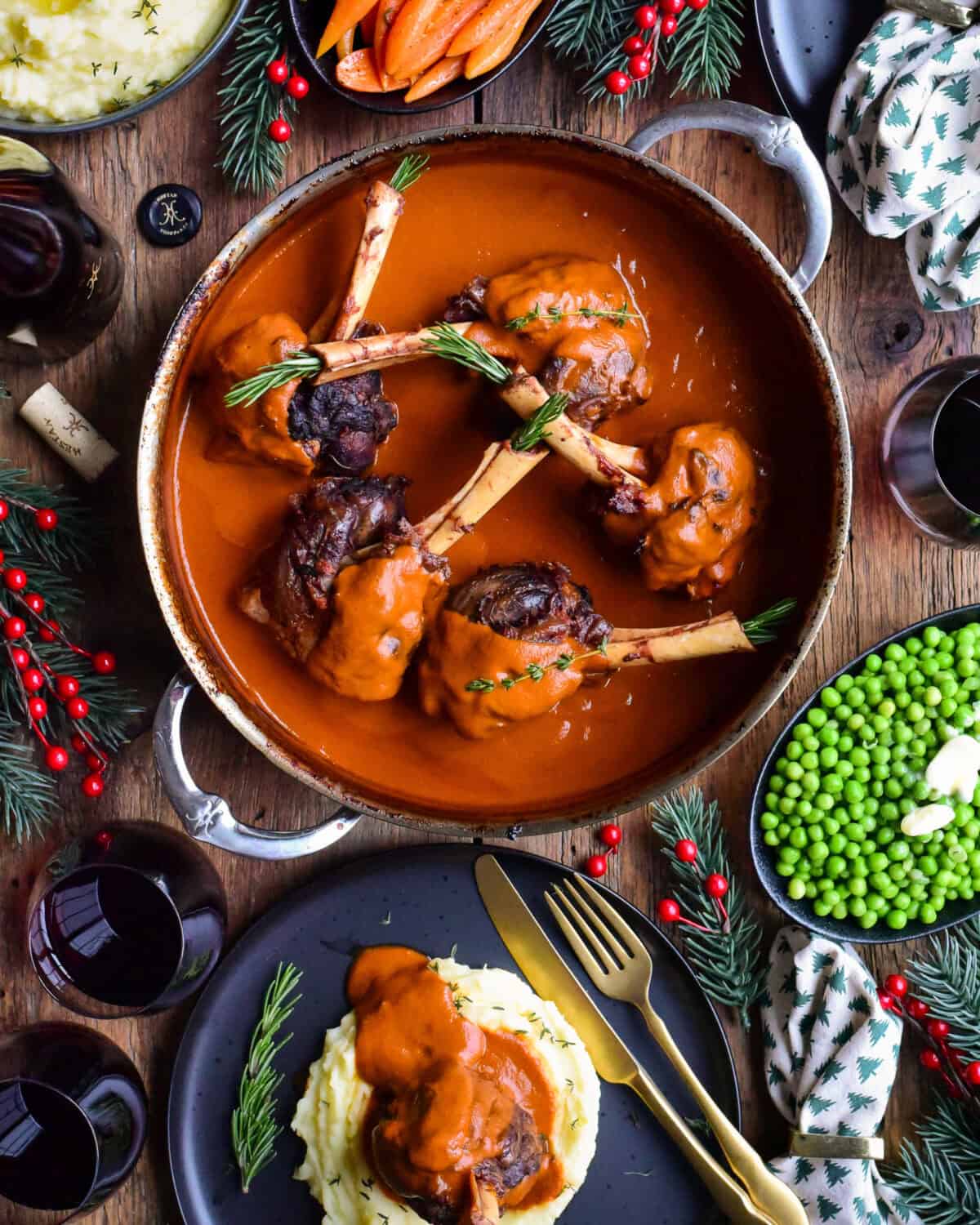 A pot with five lamb shanks in a wine tomato sauce and a plate with a lamb shank served on mashed potatoes.