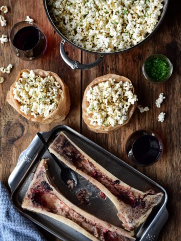 A pot and two bags of roasted bone marrow with garlic butter popcorn. Two roasted canoe bones with the bone marrow scraped out.