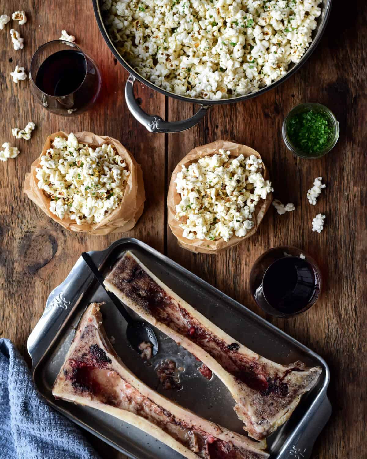 A pot and two bags of roasted bone marrow with garlic butter popcorn. Two roasted canoe bones with the bone marrow scraped out.