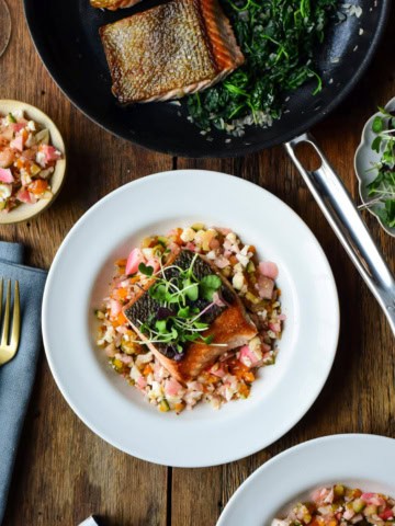 A bowl with Ora King Salmon with Spinach & Chow-Chow beside a pan of Thomas Keller's cookware.