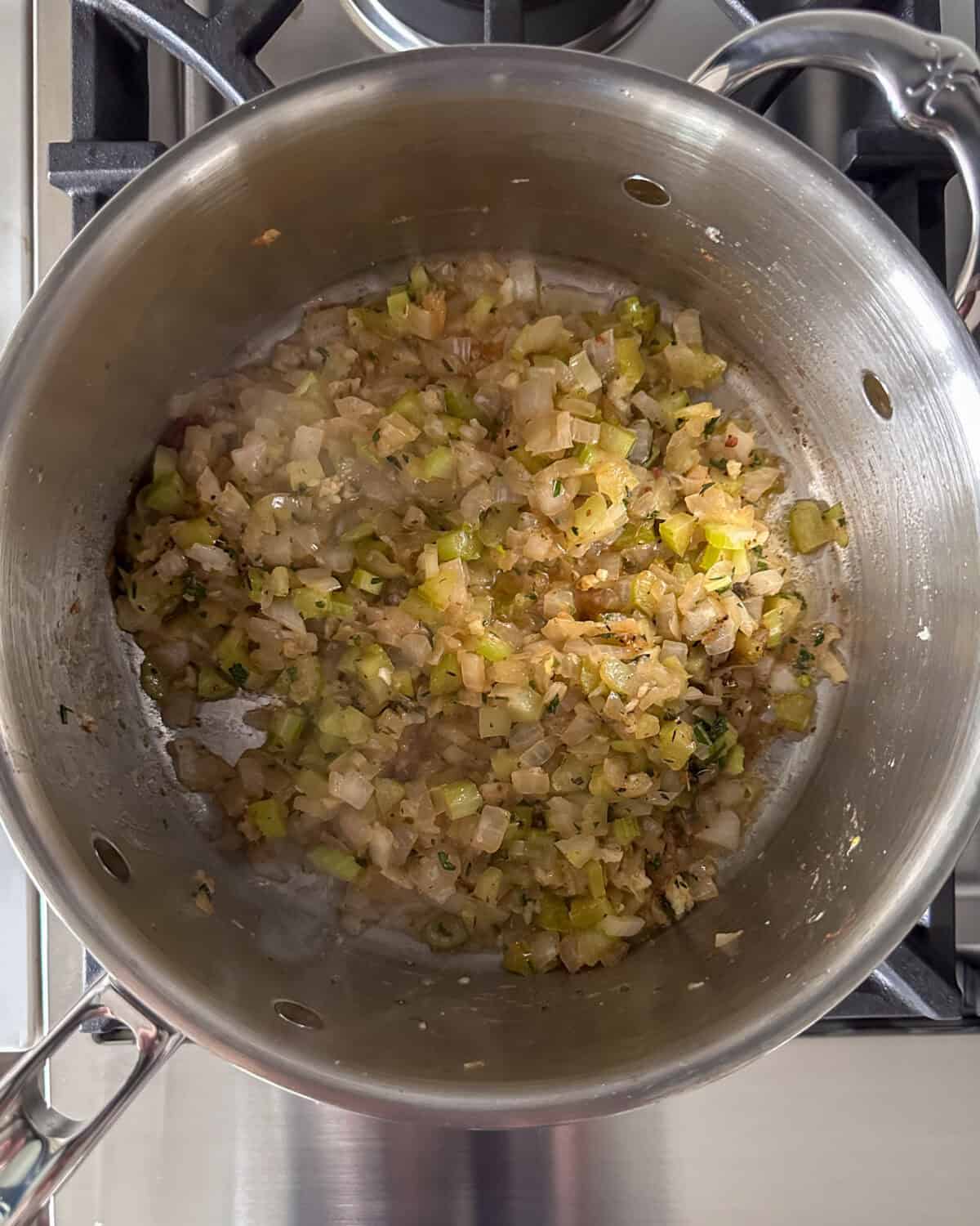 Cook the onions and celery. Toss to coat them in the bacon drippings and melted butter.