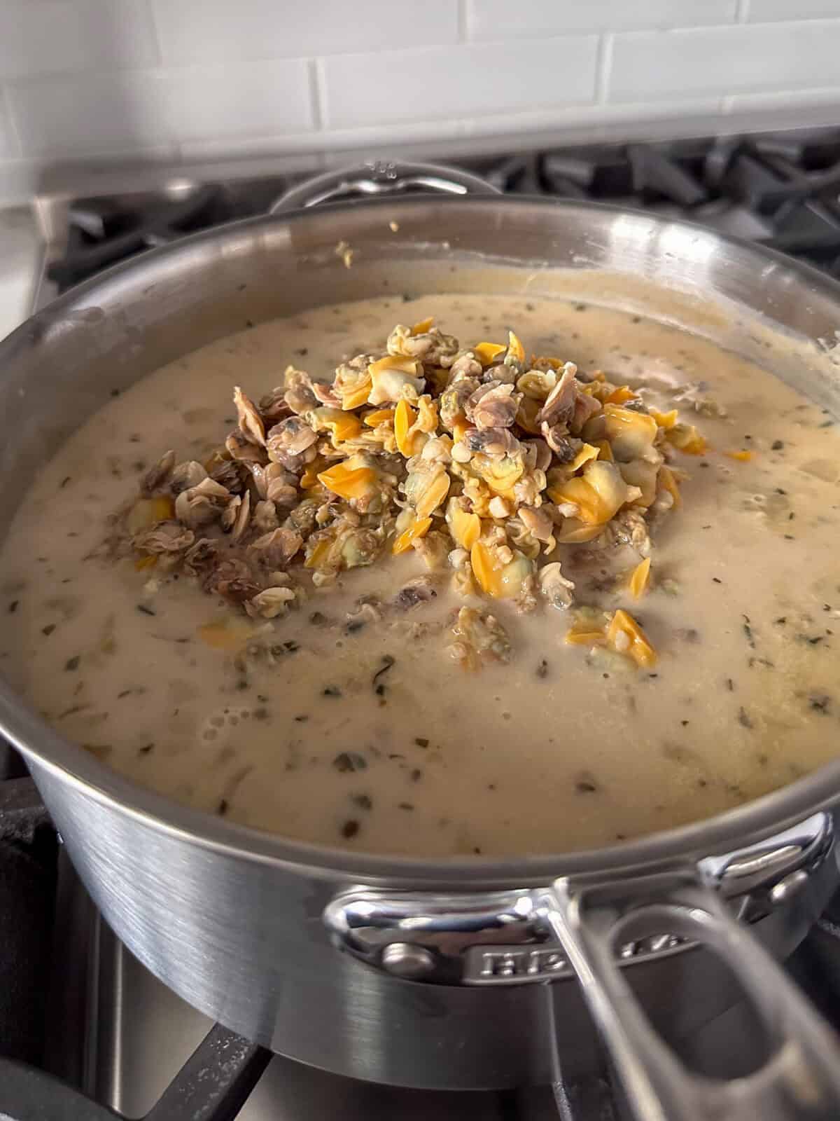 Turn the heat down to low and stir in the strained baby clams and whole clams to heat them up.