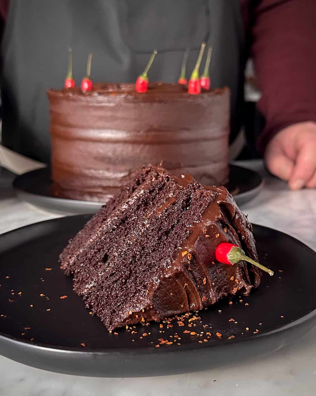 A three tired spicy chocolate cake with a Bird's Eye chilli speared in the slice.