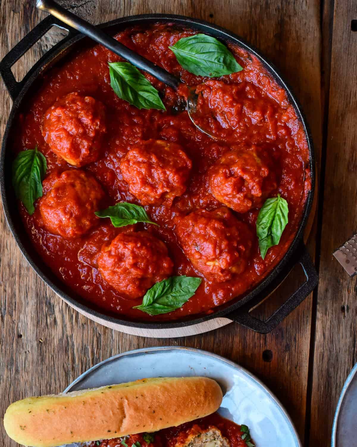 Chicken Parmesan Meatballs in a marinara sauce with basil leaves.