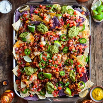 A tray of colourful and loaded chili cheese nachos.