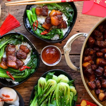 Two bowls of Chinese style braised pork belly served with steamed rice and vegetables.