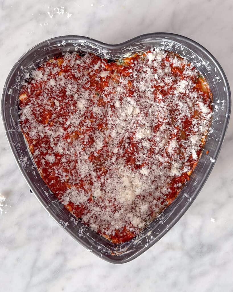 Assembling lasagna - sprinkle with Parmesan.