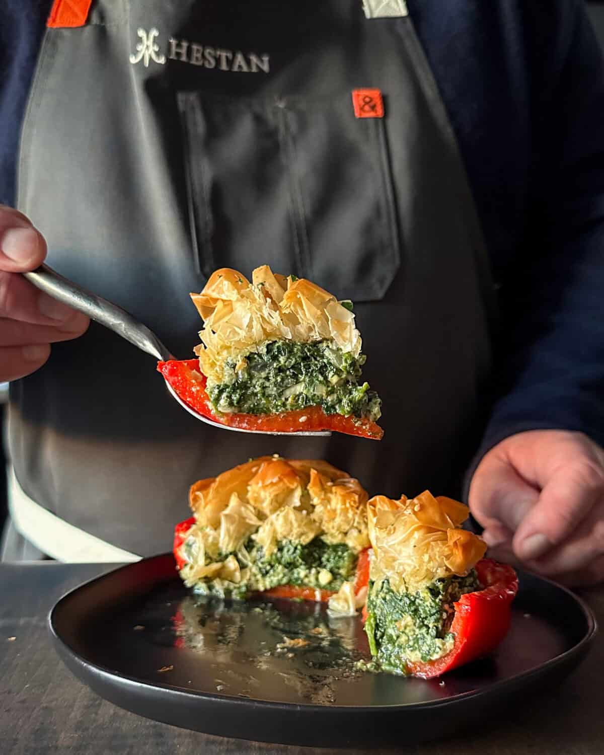 A cross section a spanakopita stuffed pepper revealing the spinach feta filling and the flaky phyllo.