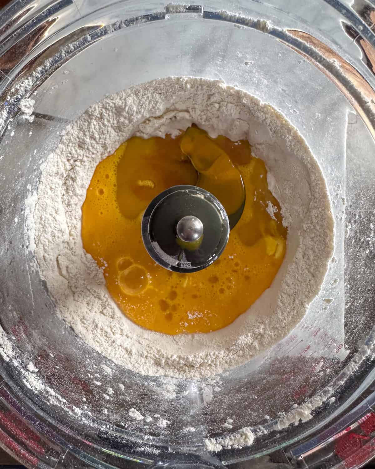 In a food processor with a dough blade, add the flour, salt, eggs, yolks, and olive oil.