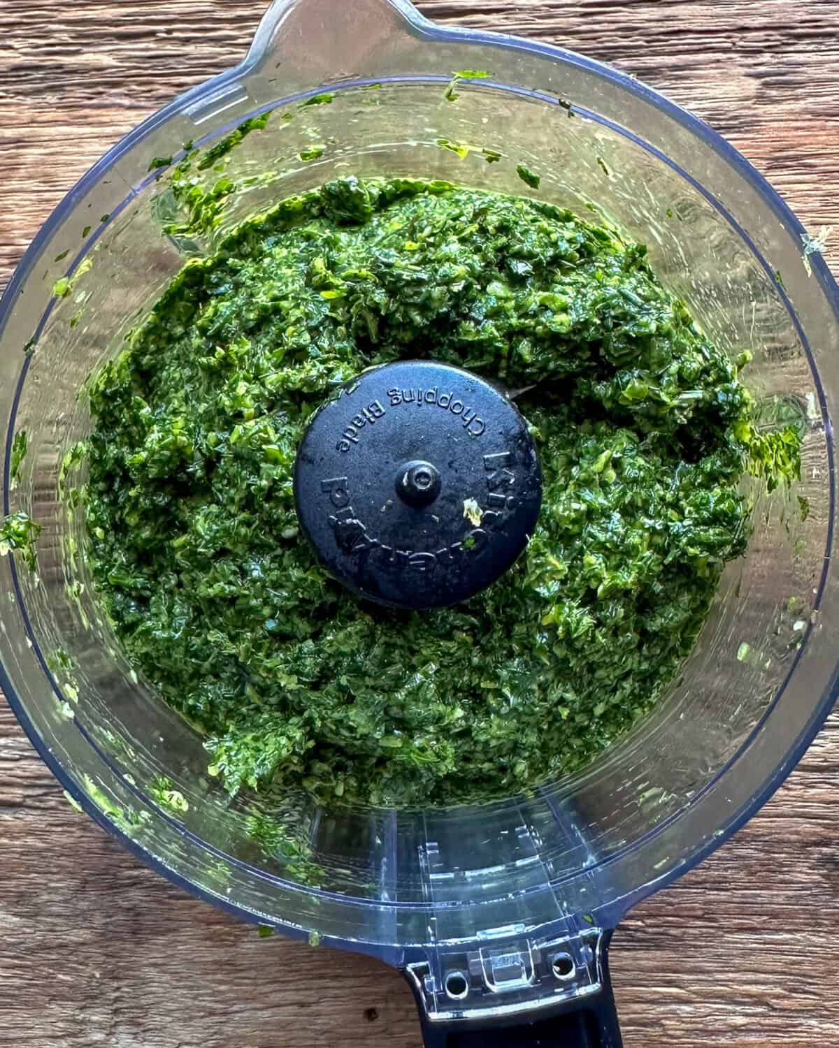 A variety of herbs blended in a mini processor for a boneless leg of lamb recipe.