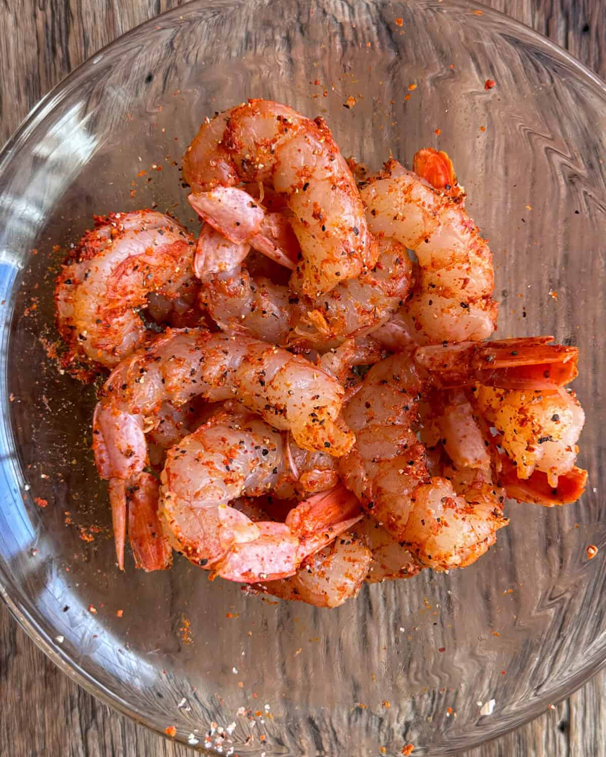 In a bowl, season the shrimp with salt, black pepper, Aleppo chili, and cayenne. Mix well to ensure the shrimp are evenly coated.