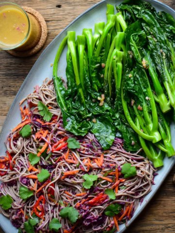 A Soba Noodle-Slaw and griddled Chinese Broccoli on a platter with a jar of ginger dressing.