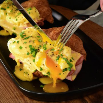 Cutting into eggs benedict with oozing yolks.