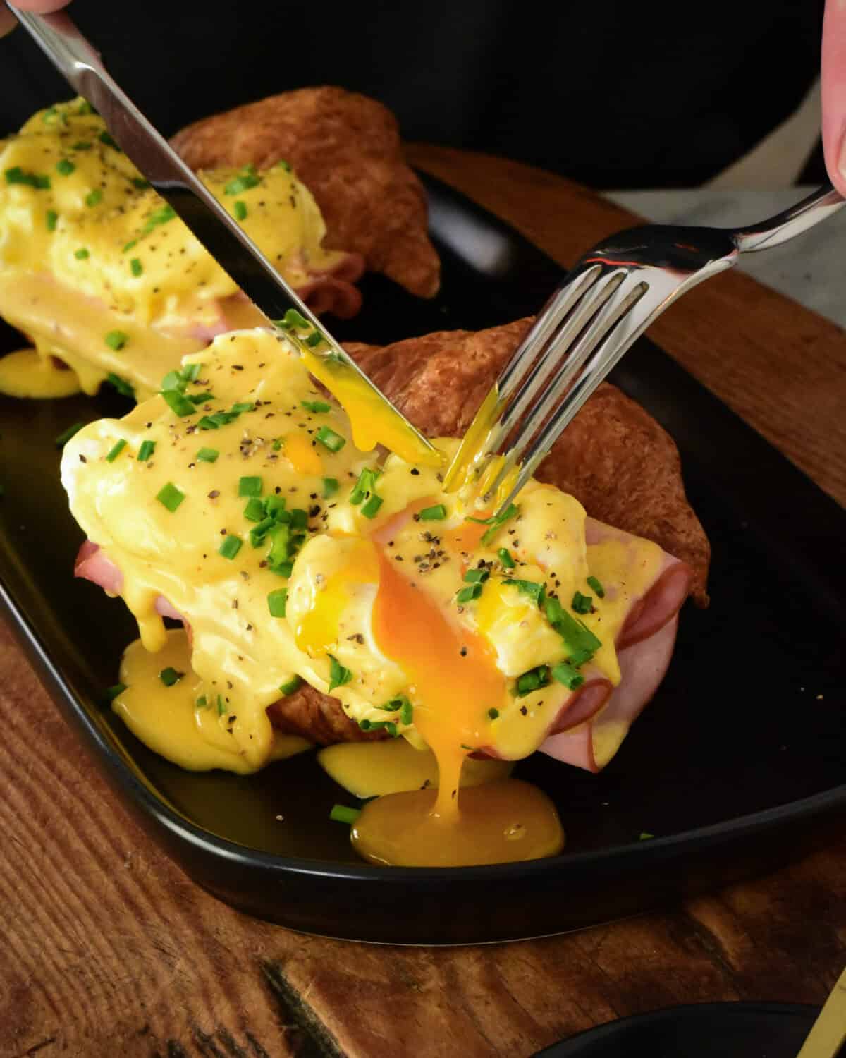Cutting into eggs benedict with oozing yolks.