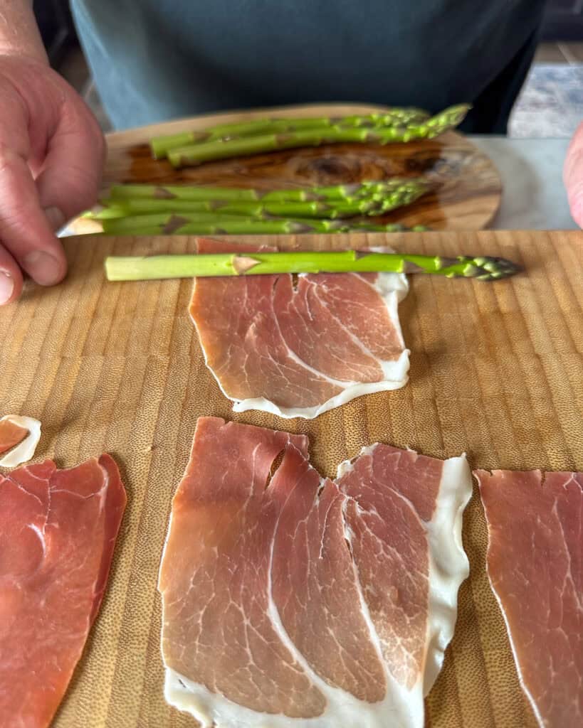 Wrap each asparagus spear, around the middle of the stalk, with a half slice of prosciutto.