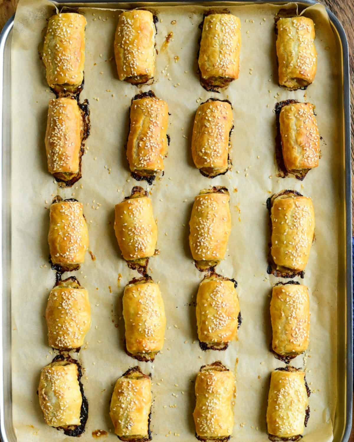 Twenty Pork, Fennel and Apple Sausage Rolls baked on a parchment lined sheet pan.