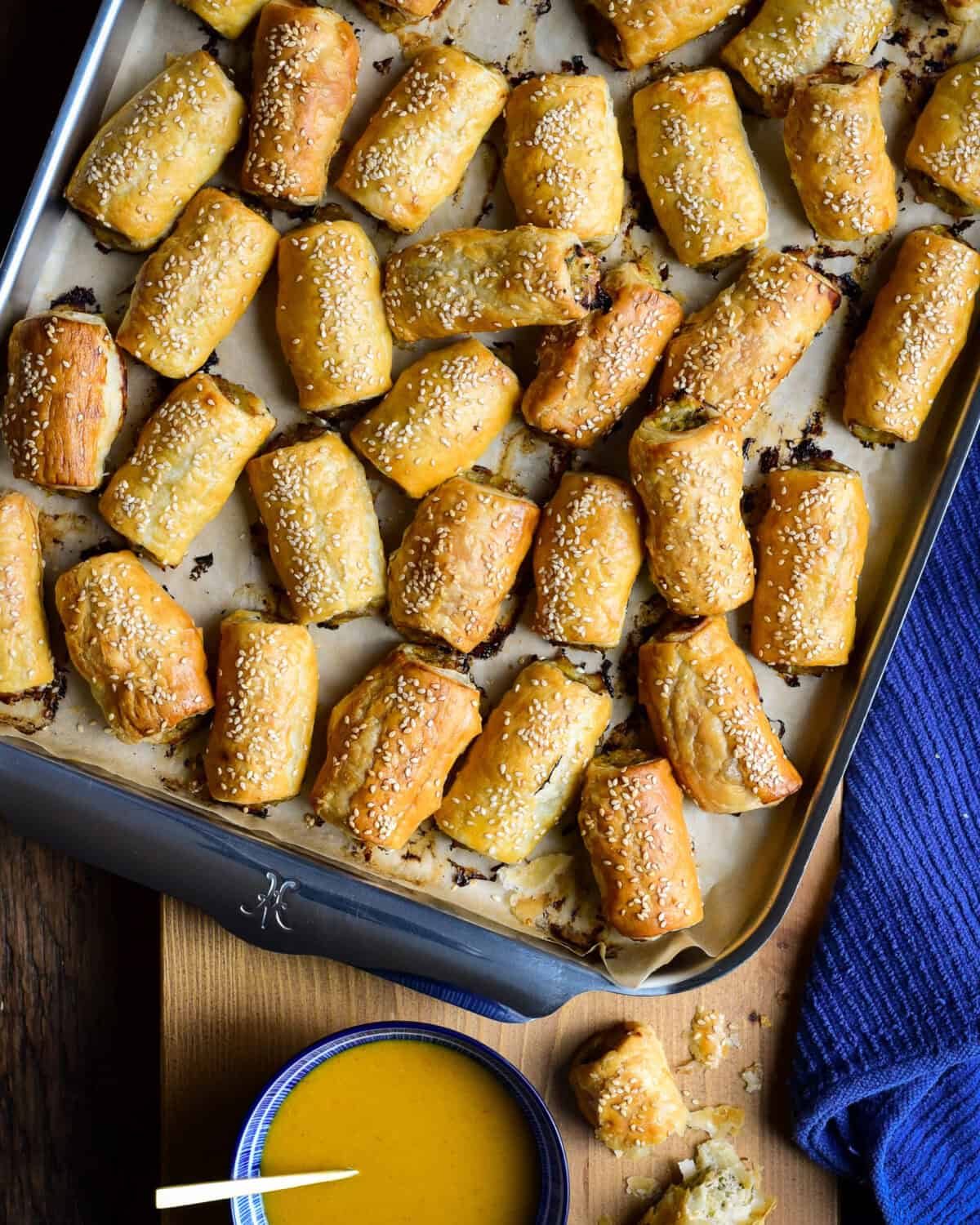 A tray of Pork, Fennel and Apple Sausage Rolls with a bowl of honey mustard dipping sauce.