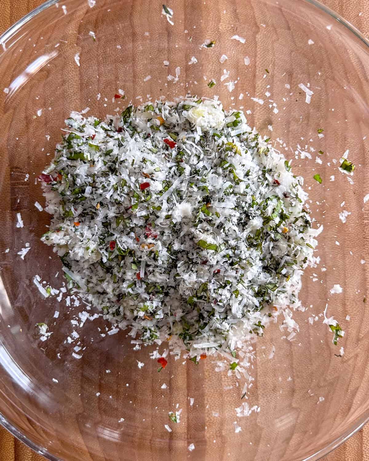 An herb-cheese mixture of oregano, basil, salt, chili flakes, cheese, and garlic into a small bowl.