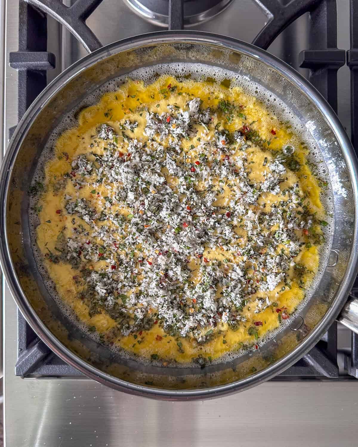 A skillet with the Dutch baby batter and herb-cheese mixture.