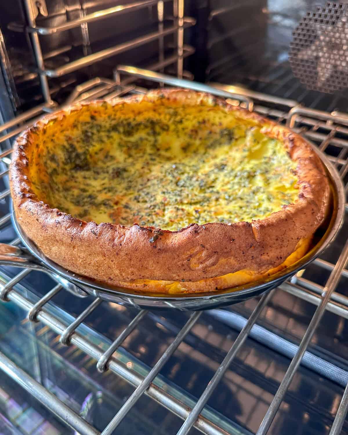 A puffed and golden Dutch baby coming out of the oven.