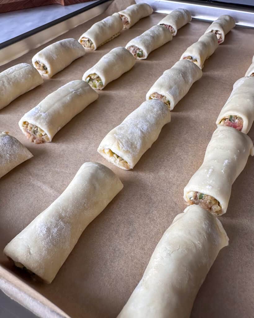 Sausage rolls cut and placed on a parchment lined sheet pan.