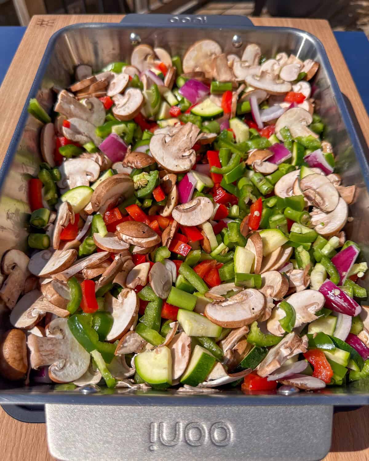 A roasting pan filled with a variety of cut vegetables ready to get roasted.