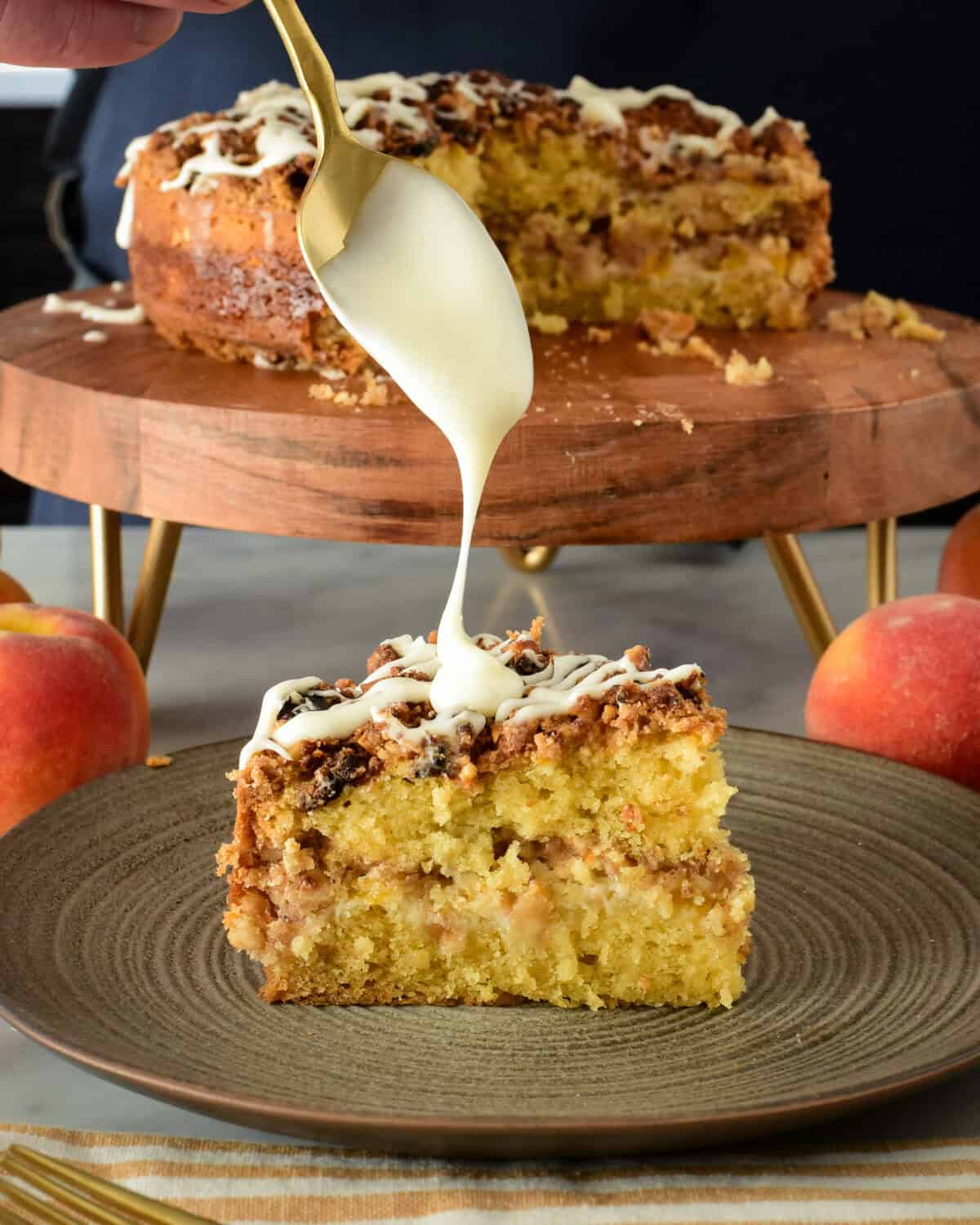 A slice of Air Fryer (Peach) Coffee Cake getting drizzled with icing with the cake in the background.