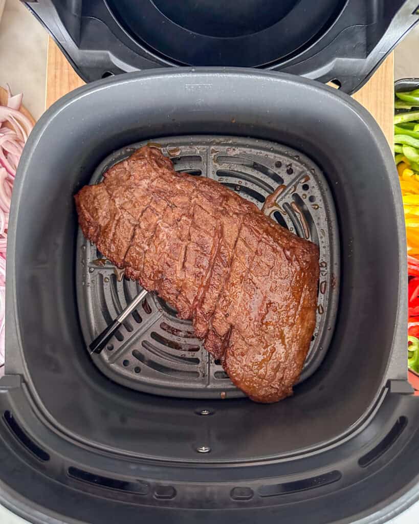 A cooked flank steak in an air fryer.