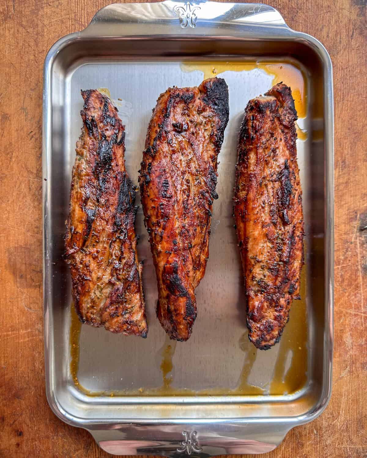 Three pork tenderloins, grilled and resting.