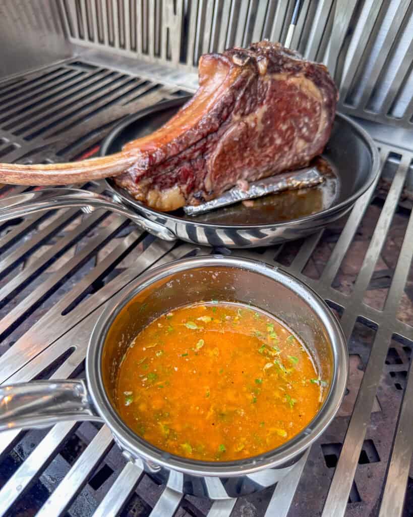A pot of cowboy butter and a ribeye searing the fat cap in a skillet.