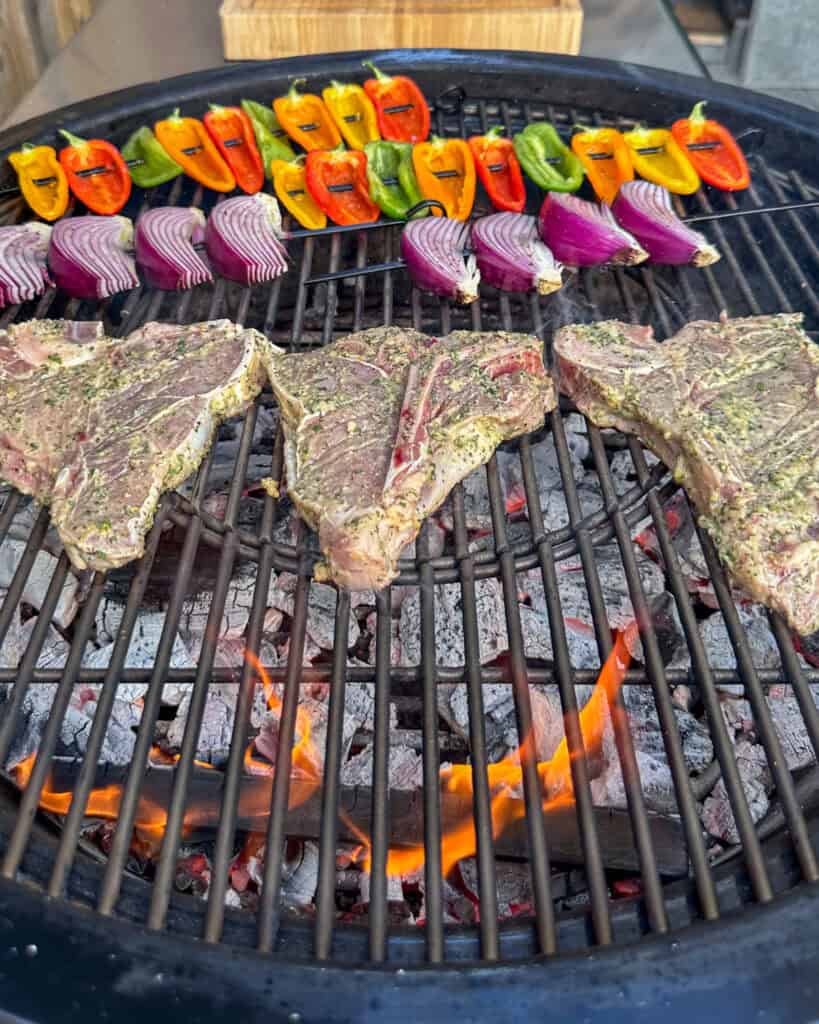 Three t bone veal chops on the bbq with vegetable skewers.