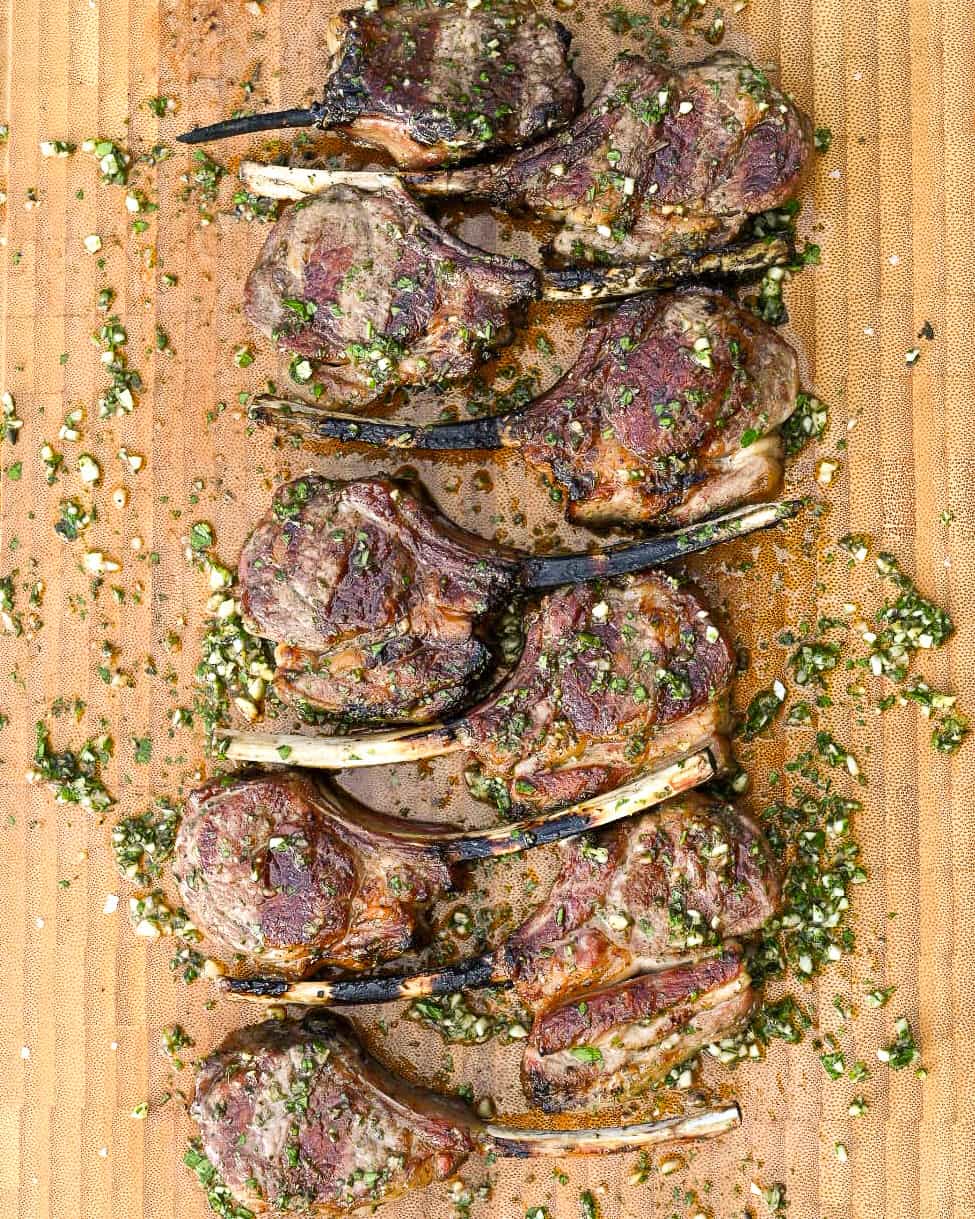 Immediately place the grilled lamb chops onto the prepared herb board sauce. Let them rest on the board for about 5 minutes.