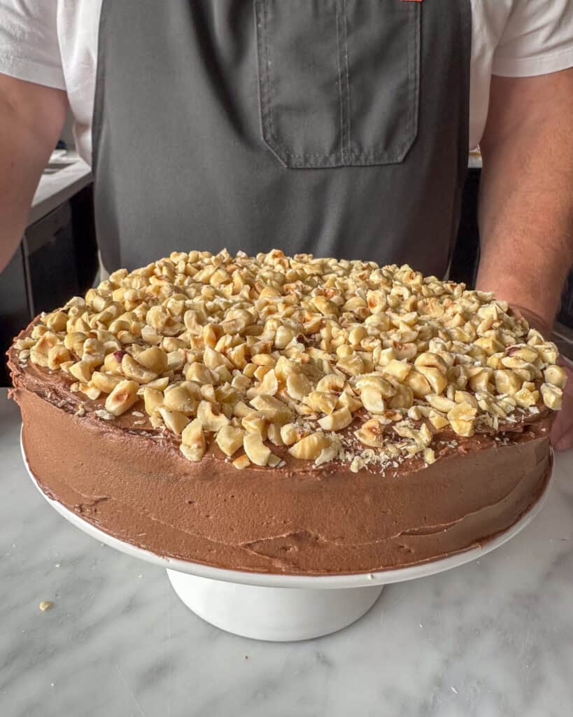 The first layer of a chocolate zucchini cake topped with chopped hazelnuts.