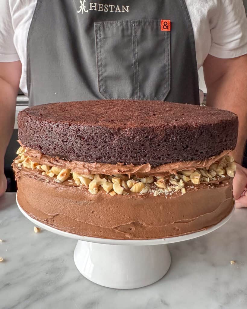 Assembling the second layer of a Chocolate Hazelnut Zucchini Layer Cake.