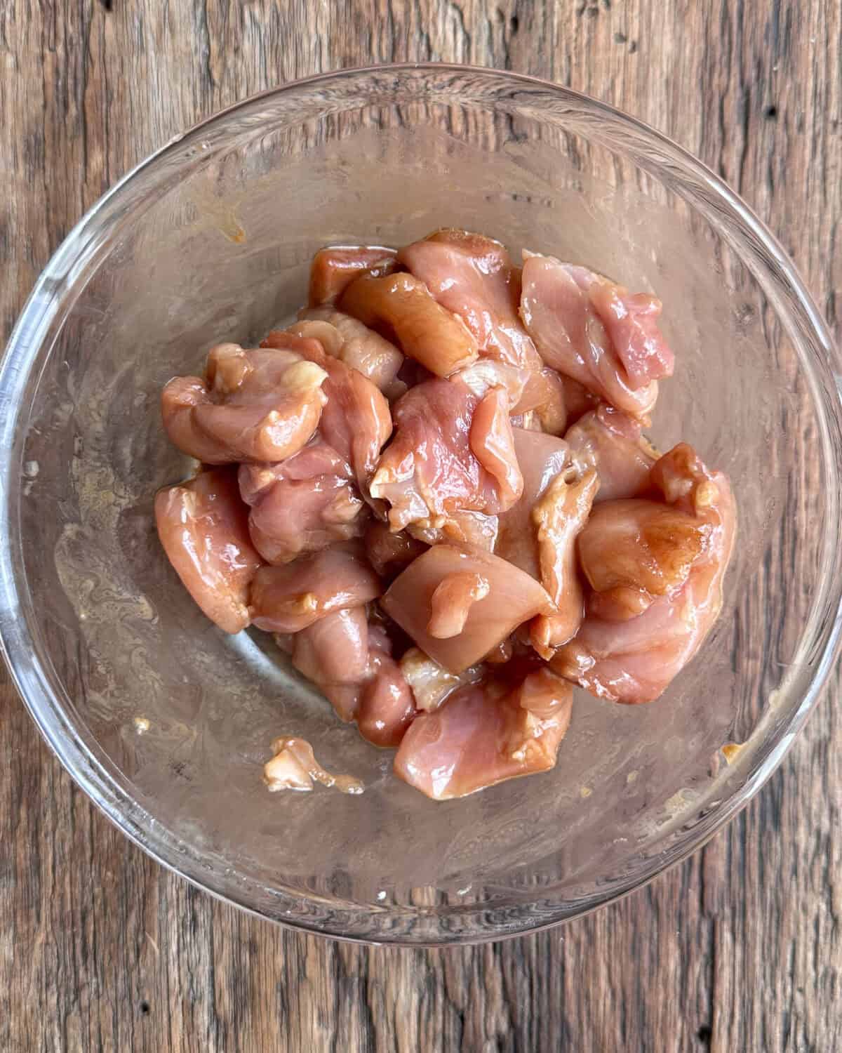 A bowl of marinated chicken for a stir fry with noodles.
