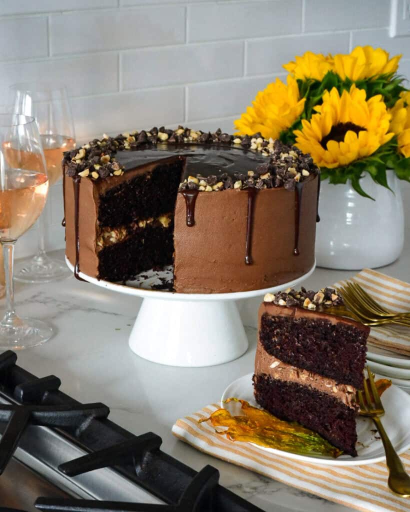 Chocolate Hazelnut Zucchini Layer Cake with a slice on a plate with a sugared zucchini blossom.