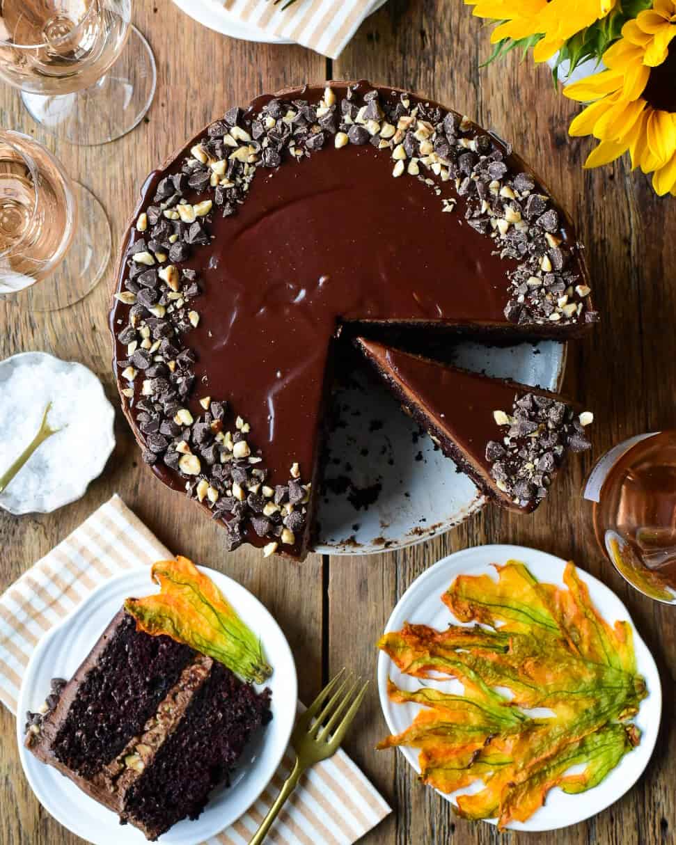 A Chocolate Hazelnut Zucchini Layer Cake with a few slices taken out. Served with Sugared Zucchini Blossoms.