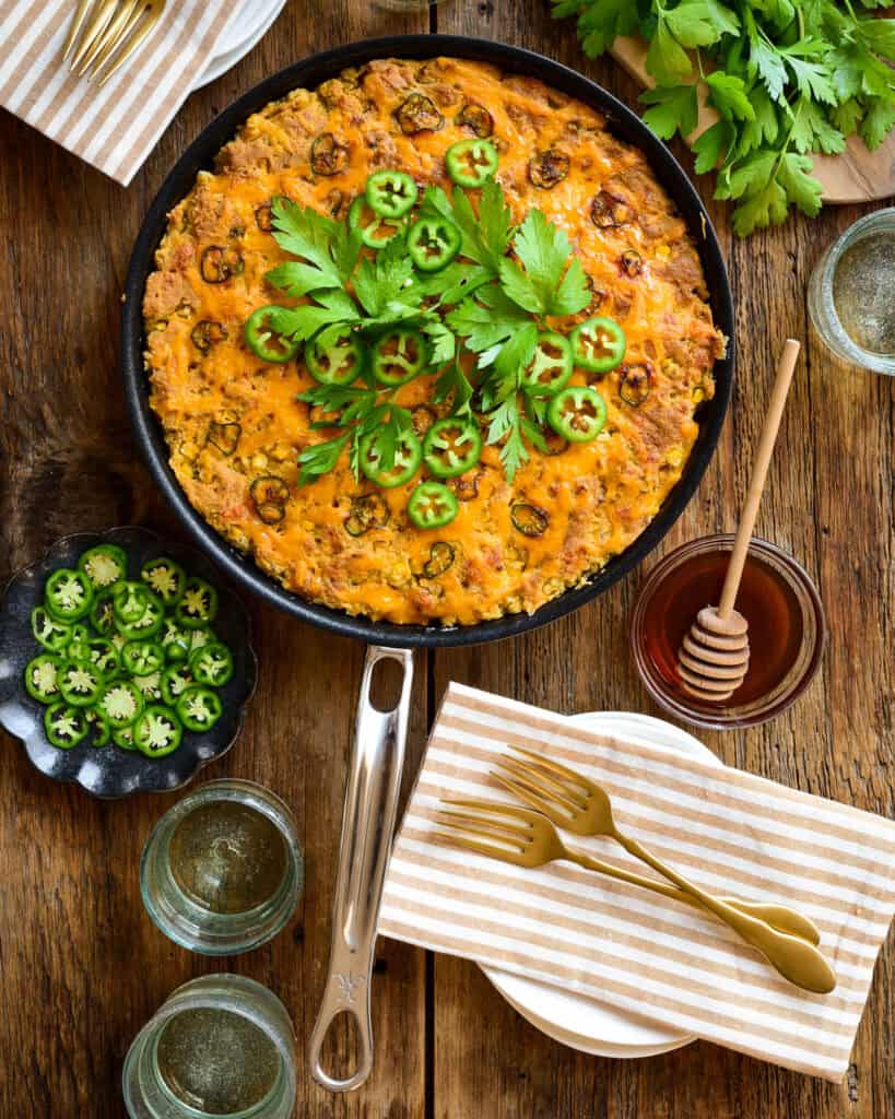 Skillet jalapeno cheddar cornbread with hot honey and fresh parslely and jalapenos.