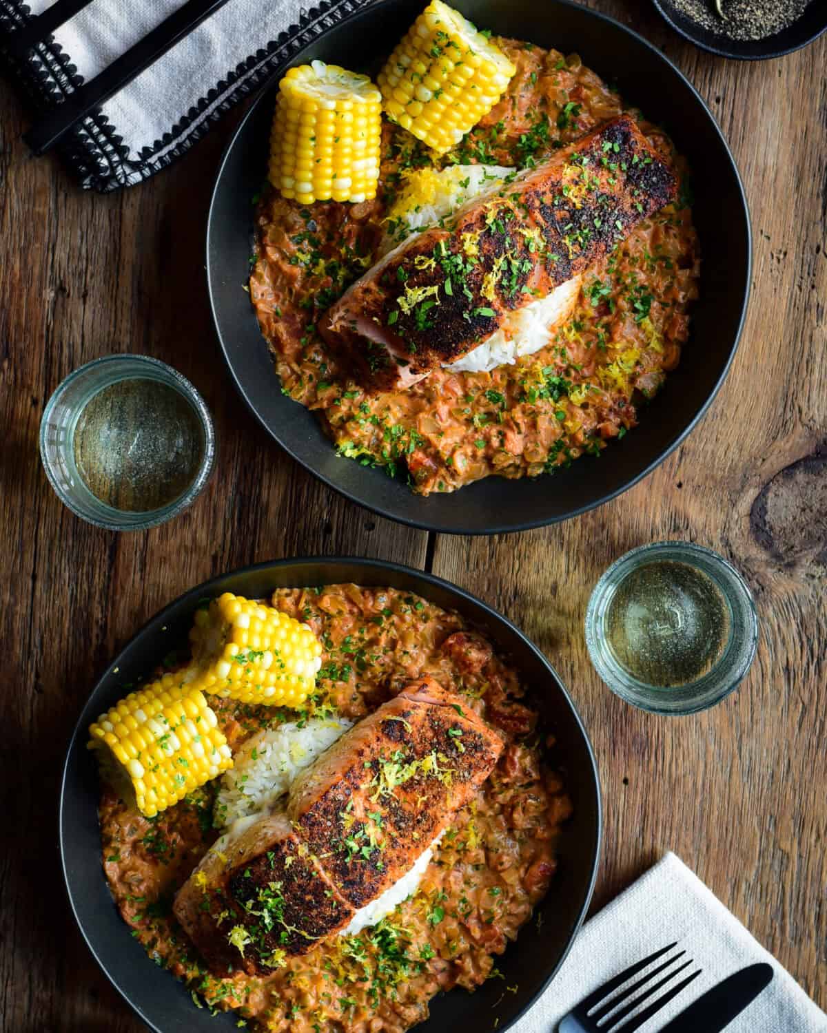 Two bowls of Blackened Salmon with a creamy Creole Sauce with rice and corn.