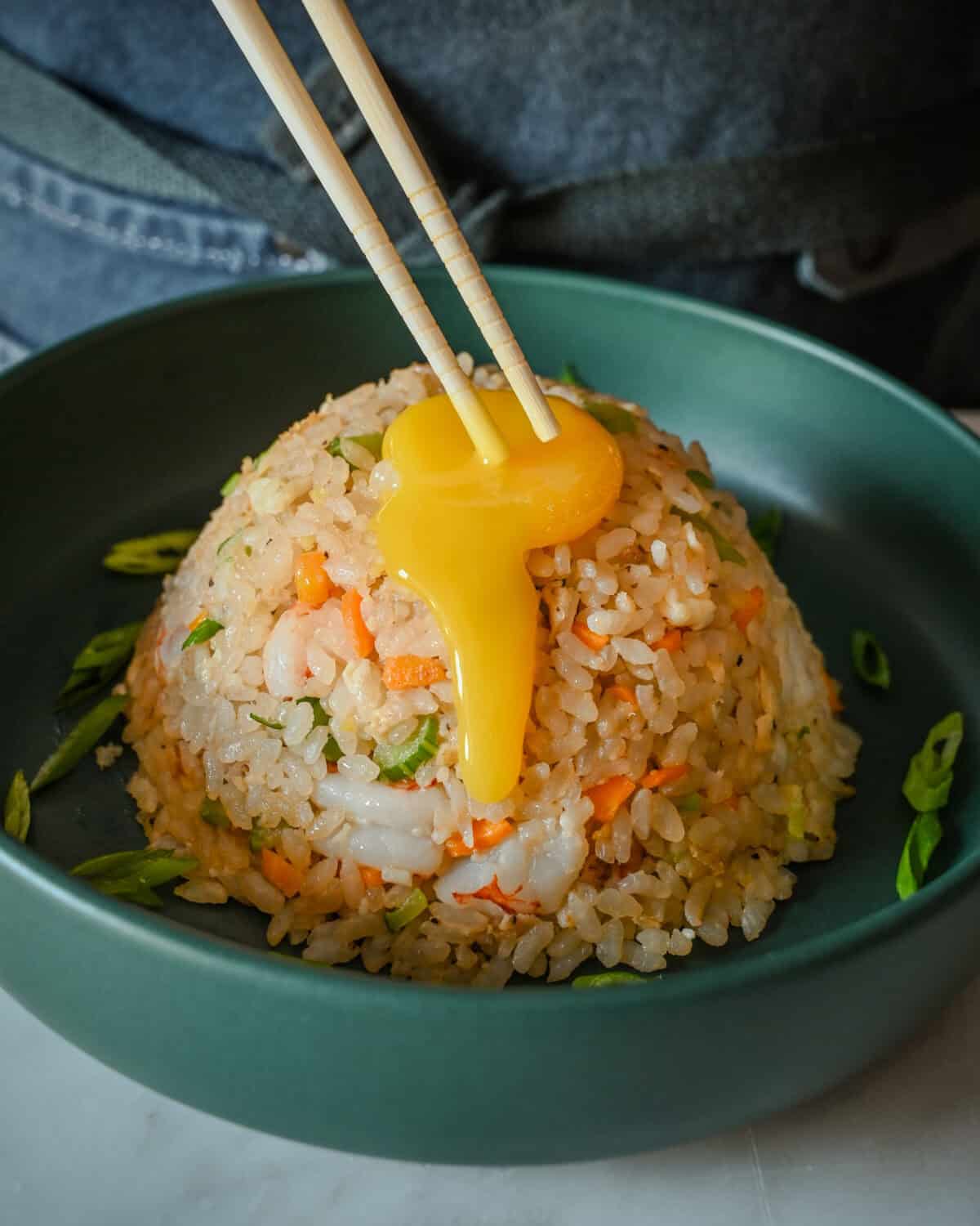 A confit egg yolk dripping down a mound of rice.