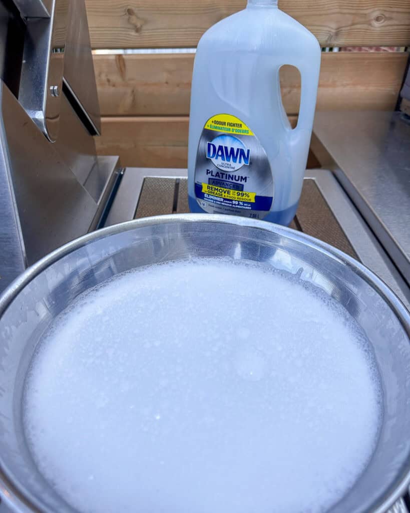 A bowl of soapy water for cleaning inside of gas grill.