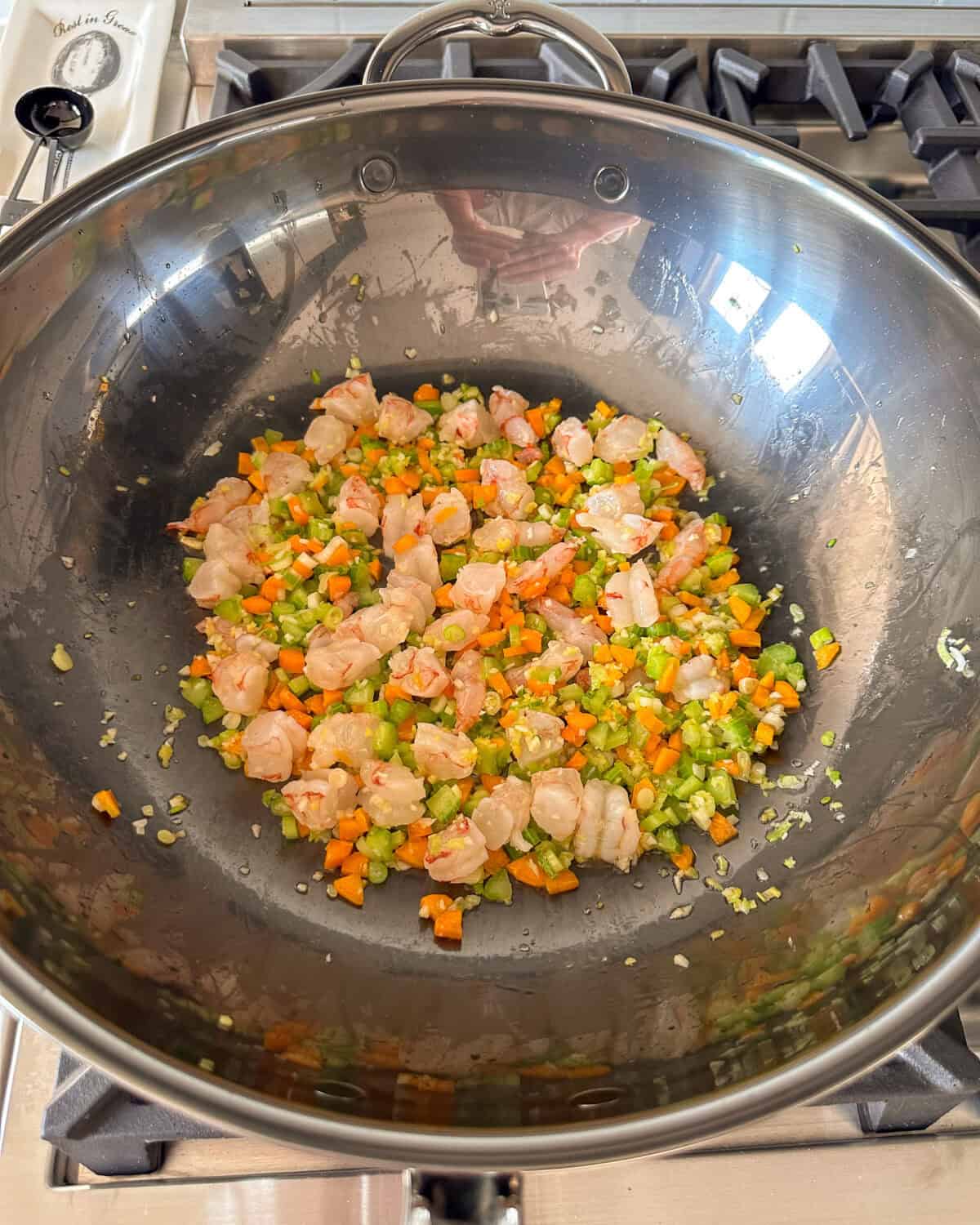 A wok with sauteed vegetables and shrimp.
