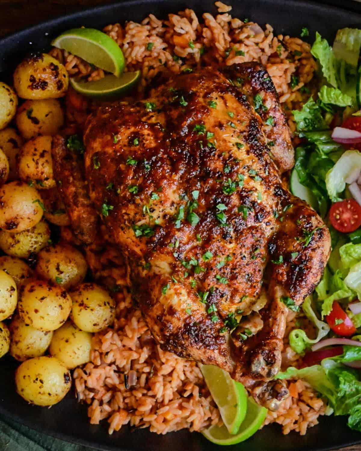 A piri-piri rotisserie chicken served with potatoes and salad.