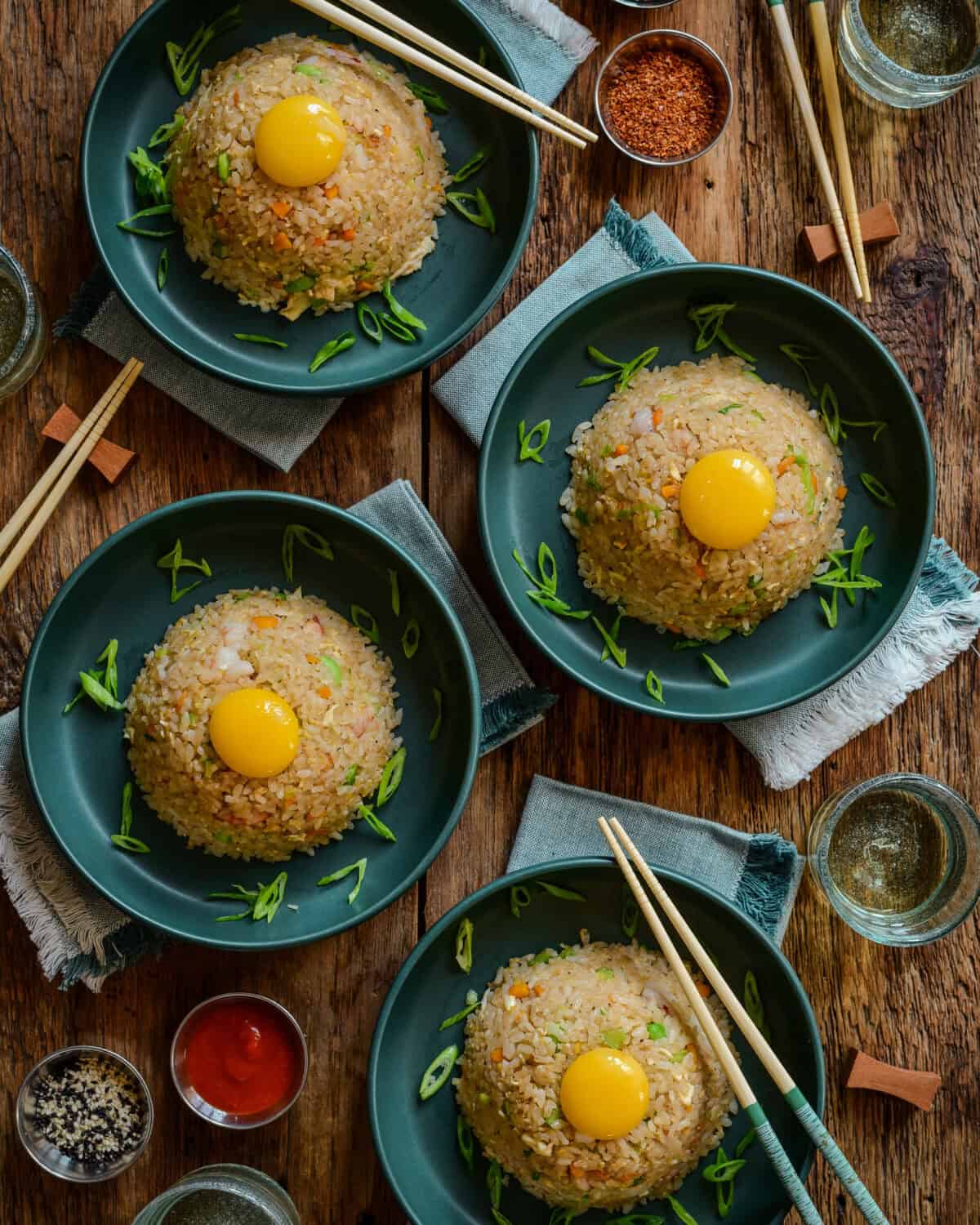 Four bowls of Japanese shrimp fried rice with a confit egg on top of each.