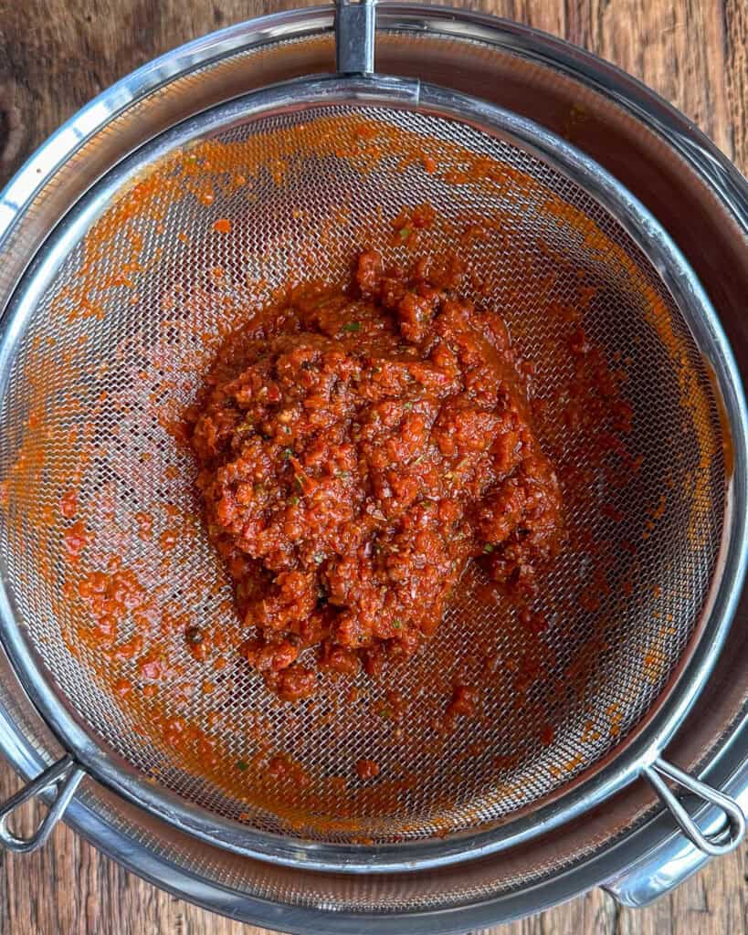 Strain the sauce through a fine mesh sieve to remove any solids, resulting in a silky-smooth adobo sauce.