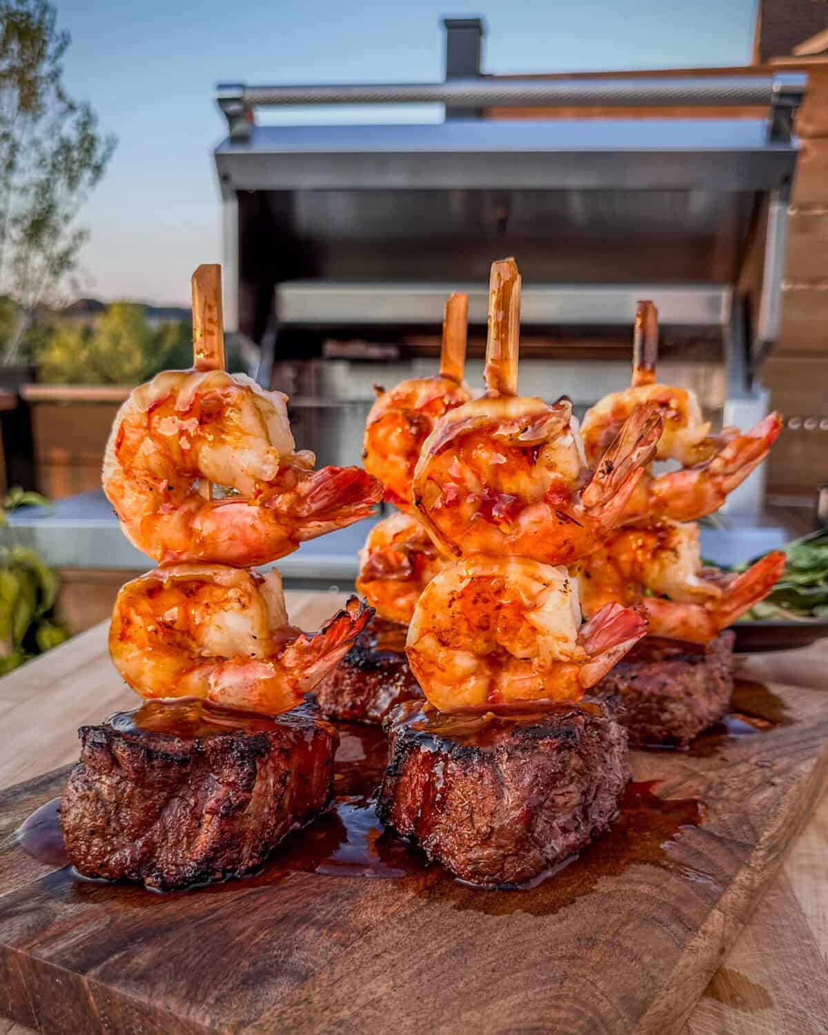 Four siroloin steaks each skewered with two shrimps and coated with teriyaki sauce.