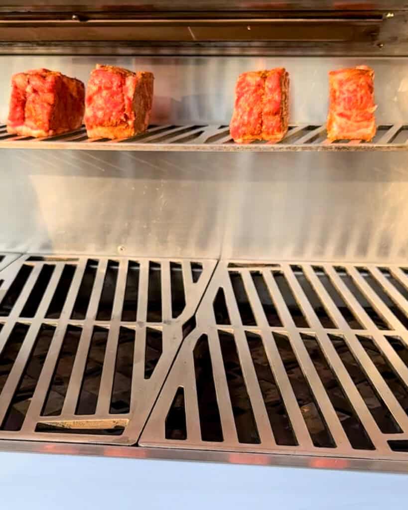 Place the steaks, fat side down on the upper rack of your cold gas grill.
